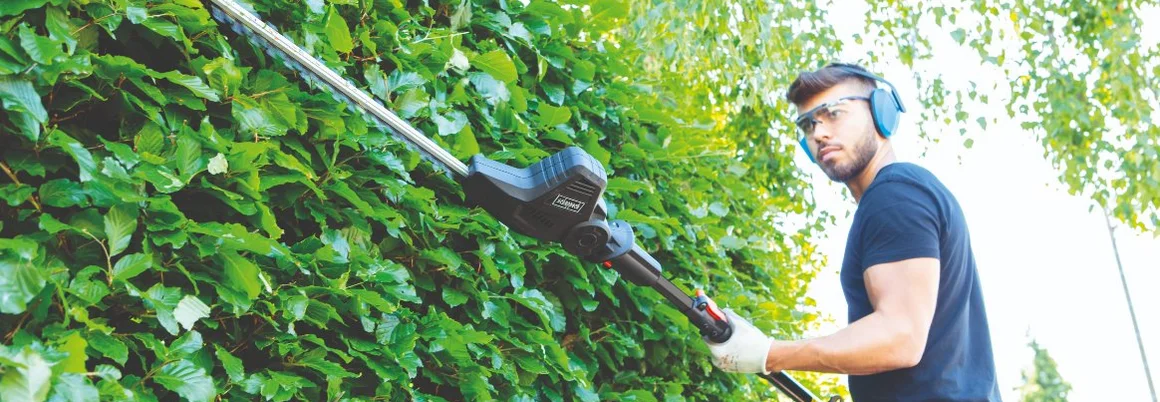 Person schneidet Hecke mit Teleskop-Heckenschere